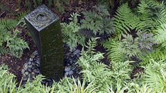 Outdoor water sculpture with ferns and rocks